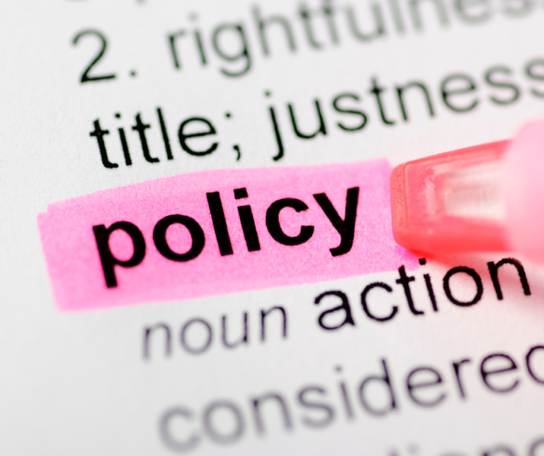 The word "policy" highlighted in pink on a printed document, with a highlighter pen visible.