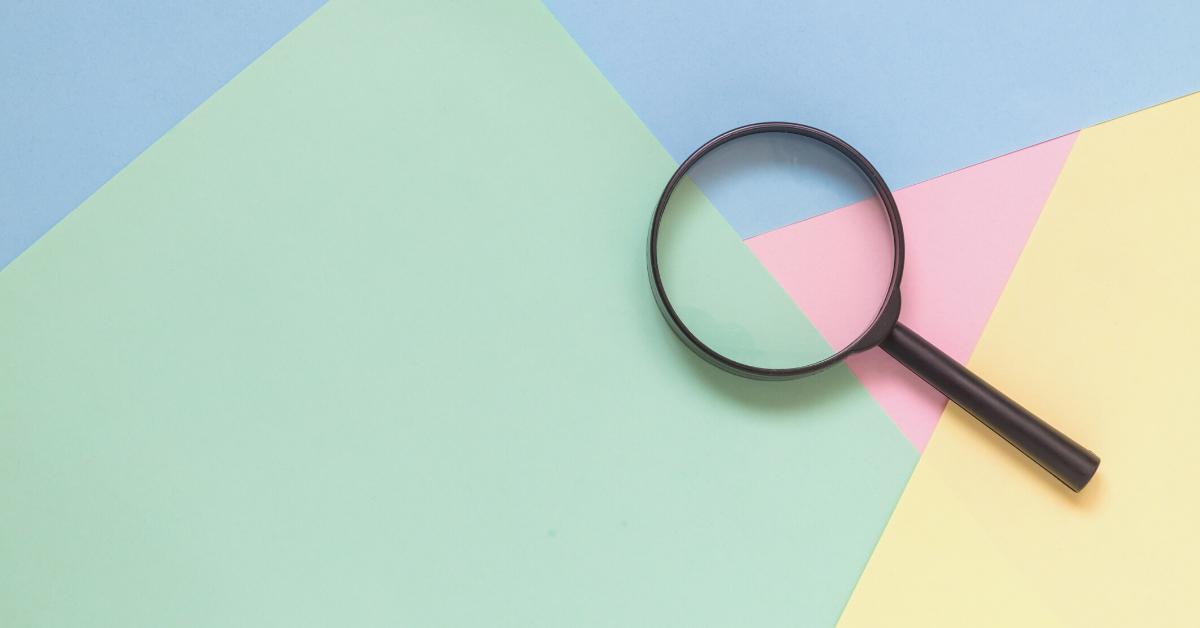 A black magnifying glass rests on a pastel-colored paper background with shades of blue, green, pink, and yellow.